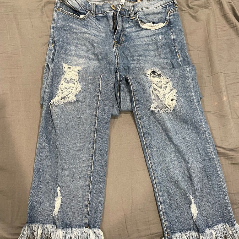Distressed sneak peek jeans with frayed bottoms and holes in the knees